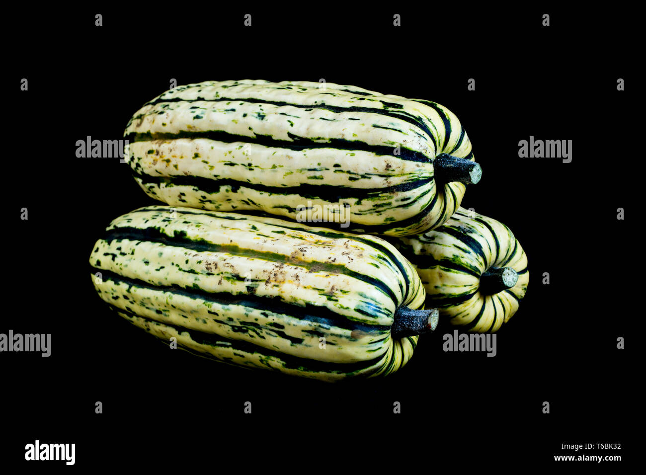 Close up of three Delicata squash on black background. Stock Photo