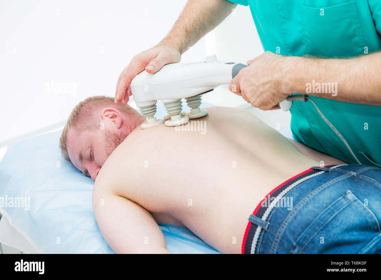 Doctor does transcranial magnetic stimulation, electrotherapeutic treatment of the back. A chiropractor treats patient's thoracic spine. Physiotherapy Stock Photo