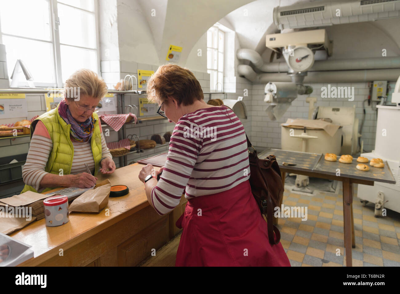 Salzburg bakery, view of a middle aged woman buying bread inside the oldest bakery in Salzburg Old Town, the Stiftsbackerei St Peter, Austria. Stock Photo