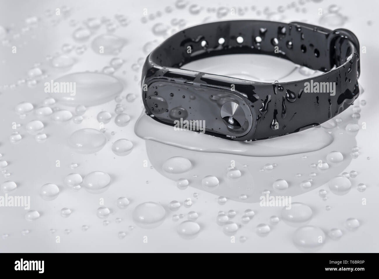 Wet fitness bracelet, fitness tracker on a white glossy background with drops of water Stock Photo