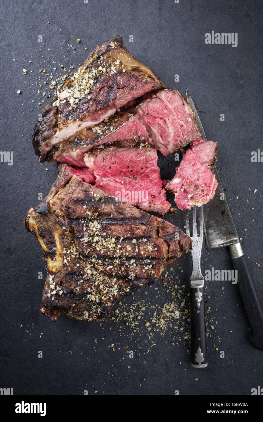 Barbecue dry aged Rib of Beef as closeup on a black slate Stock Photo