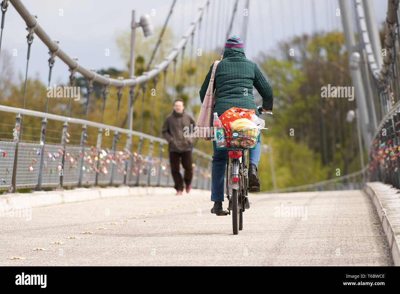 cyclist and pedestrian on a suspension bridge in Magdeburg Stock Photo