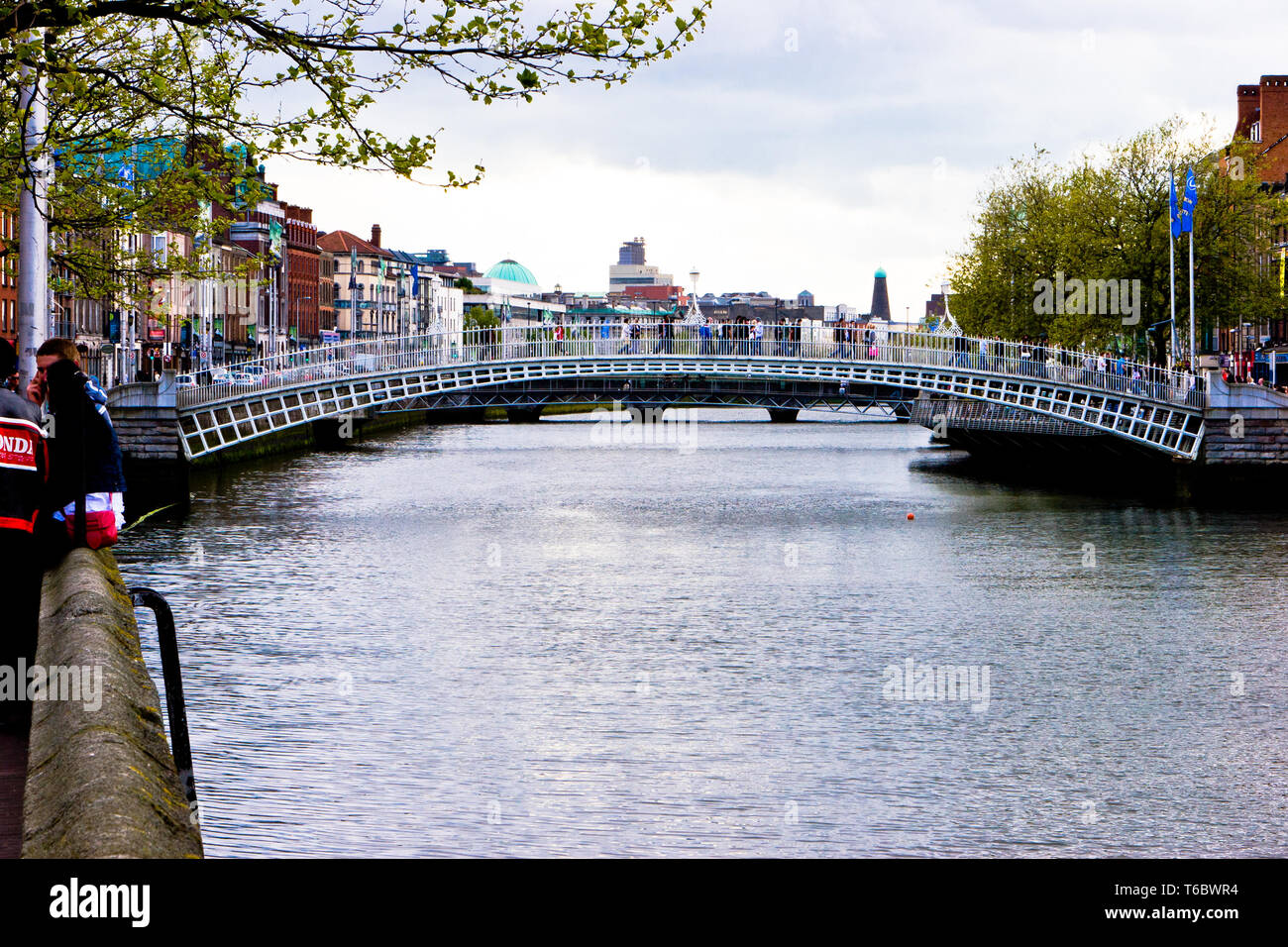 People crossing Ha'penny Bridge over the River Liffey in Dublin ...