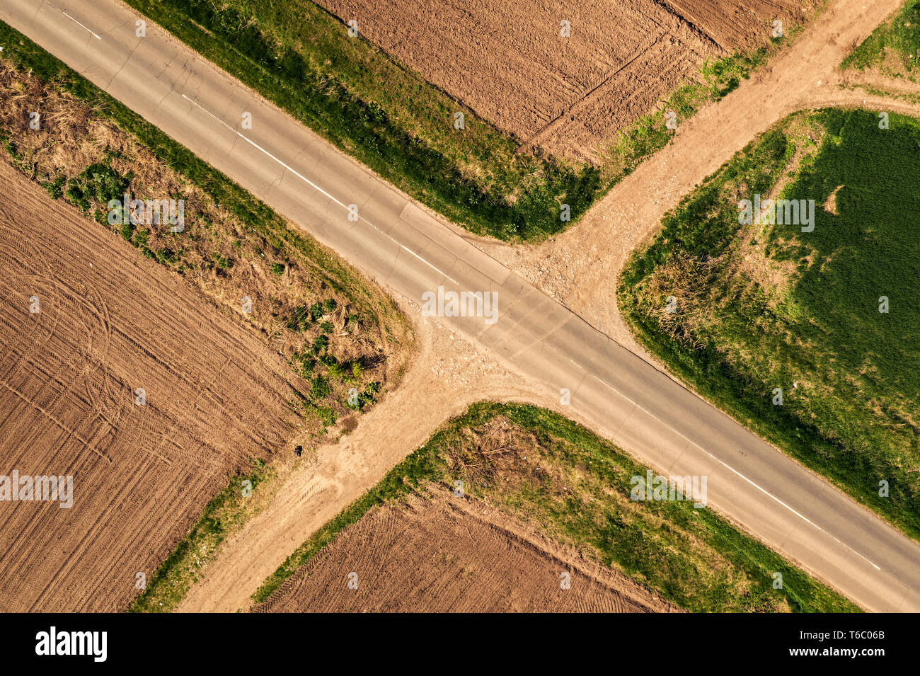 Aerial view of roadway and dirt road intersection, top down from drone pov Stock Photo