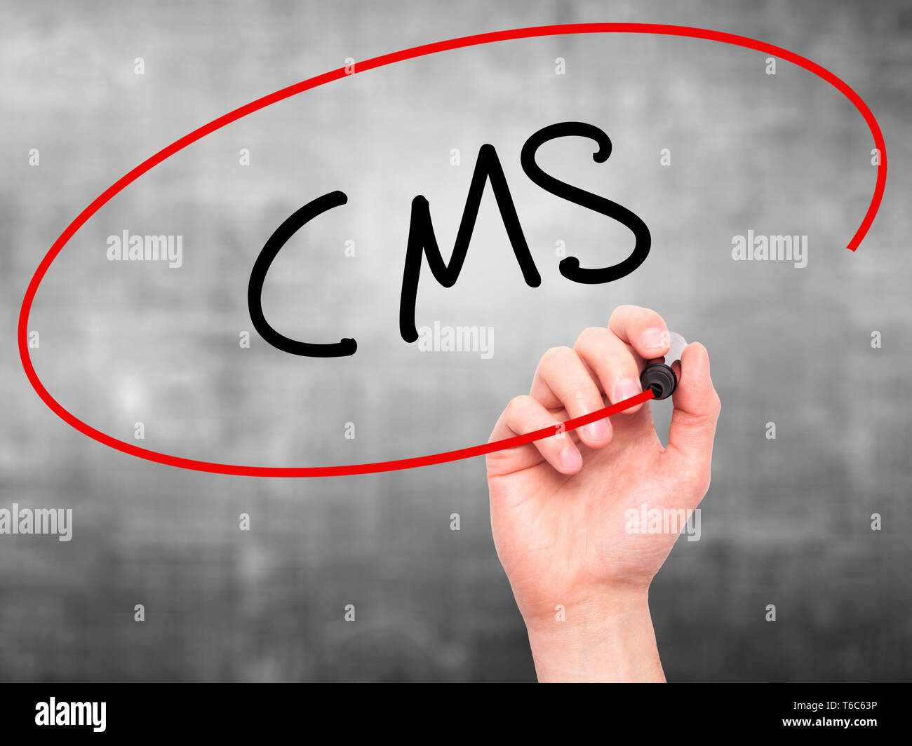 Man Hand writing CMS (Custom Management System) with black marker on visual screen Stock Photo