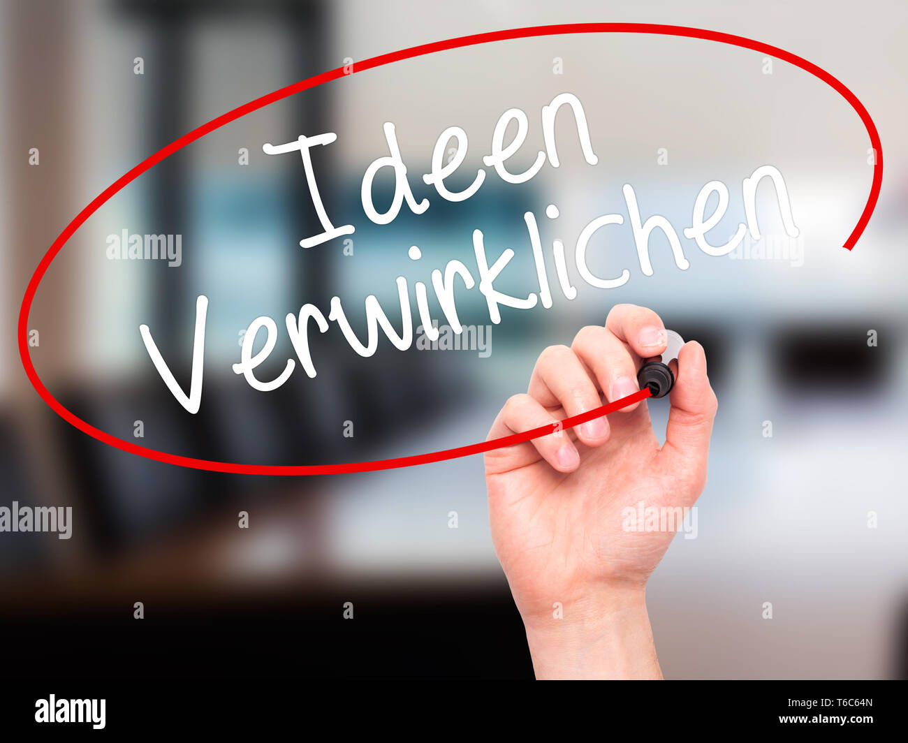 Man Hand writing Ideen Verwirklichen ( Realize Ideas in German) with black marker on visual screen Stock Photo