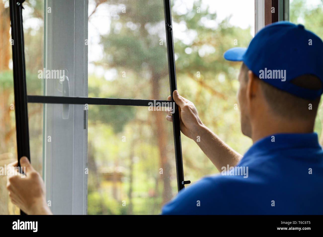 man installing insect mesh screen to protect room from mosquito Stock Photo