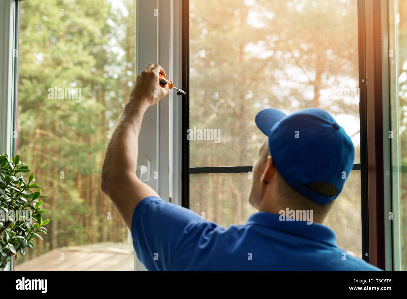 man installing mosquito net wire screen on house window Stock Photo