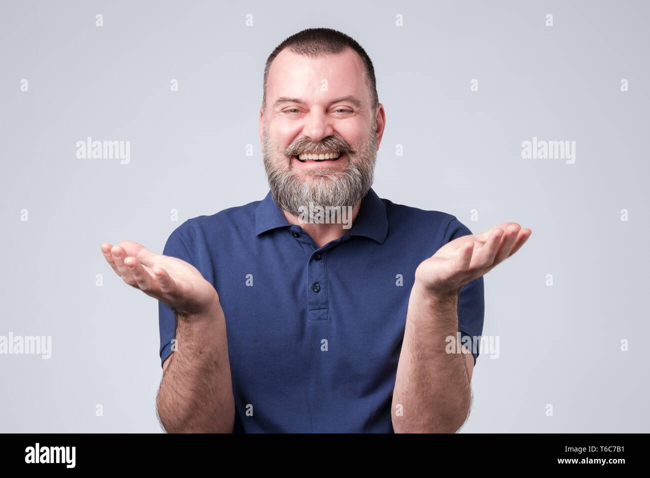 Man with beard in blue t-shirt laughing out loud, talking with friends, telling funny jok Stock Photo