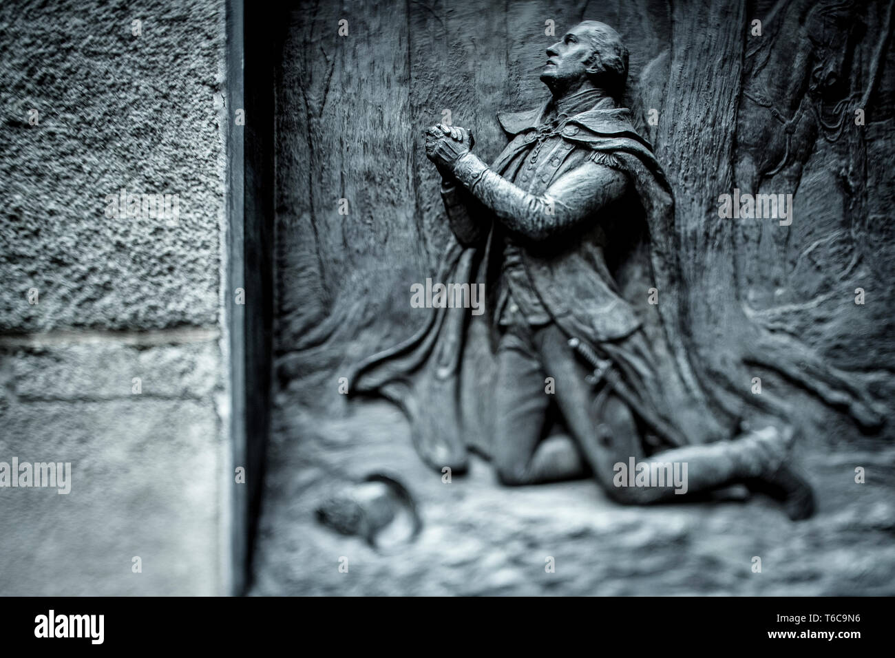 A brass relief of George Washington kneeling in prayer at Valley Forge. The relief, made by artist James E. Kelly in 1904, is on the side of the stairs leading to the Federal Hall near Wall Street, where George Washington was sworn in as Americas first President. Stock Photo