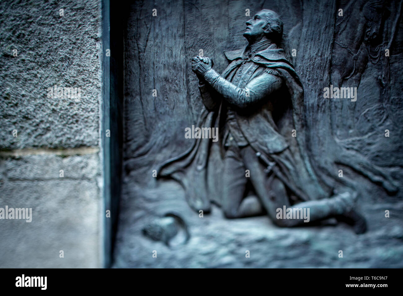 A brass relief of George Washington kneeling in prayer at Valley Forge. The relief, made by artist James E. Kelly in 1904, is on the side of the stairs leading to the Federal Hall near Wall Street, where George Washington was sworn in as Americas first President. Stock Photo