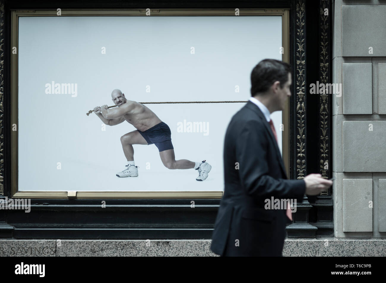 A floor specialist, stock broker, walks past an ad for the NYSC New York Sports Club. This particular NYSC gym is on Wall Street, right next to the NYSE Euronext Stock Exchange. Stock Photo