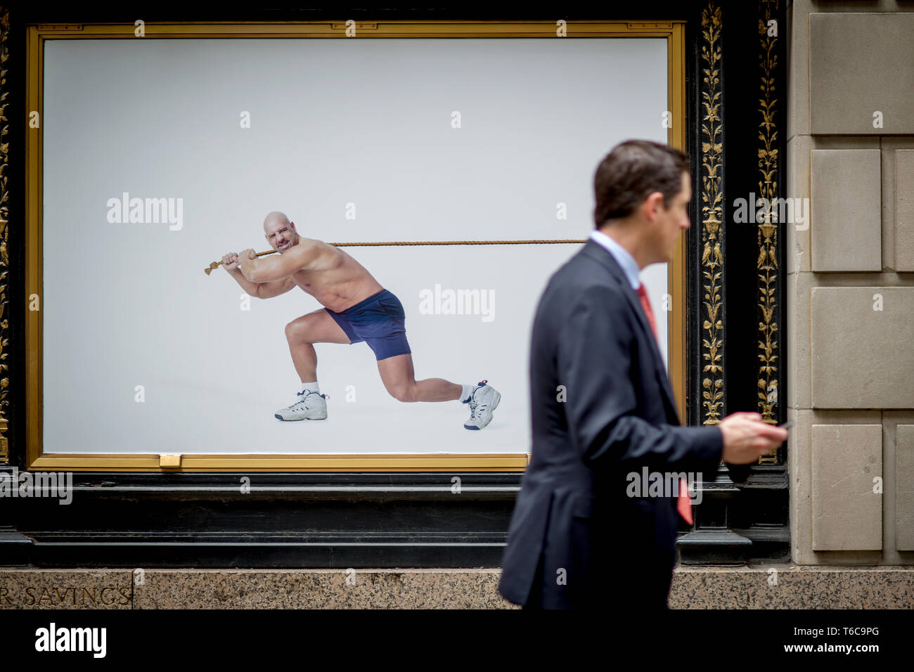 A floor specialist, stock broker, walks past an ad for the NYSC New York Sports Club. This particular NYSC gym is on Wall Street, right next to the NYSE Euronext Stock Exchange. Stock Photo