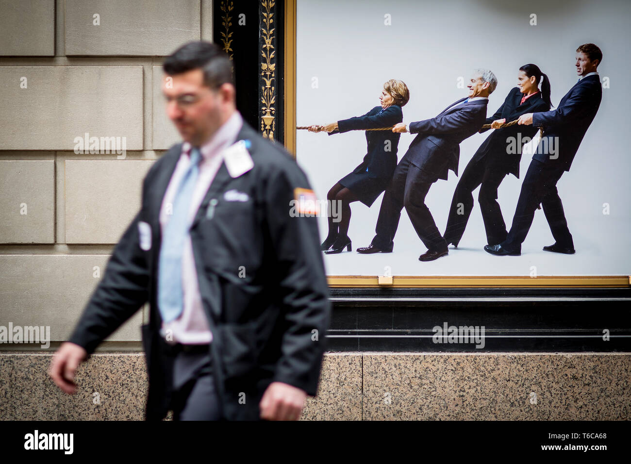 A floor specialist, stock broker, walks past an ad for the NYSC New York Sports Club. This particular NYSC gym is on Wall Street, right next to the NYSE Euronext Stock Exchange. Stock Photo