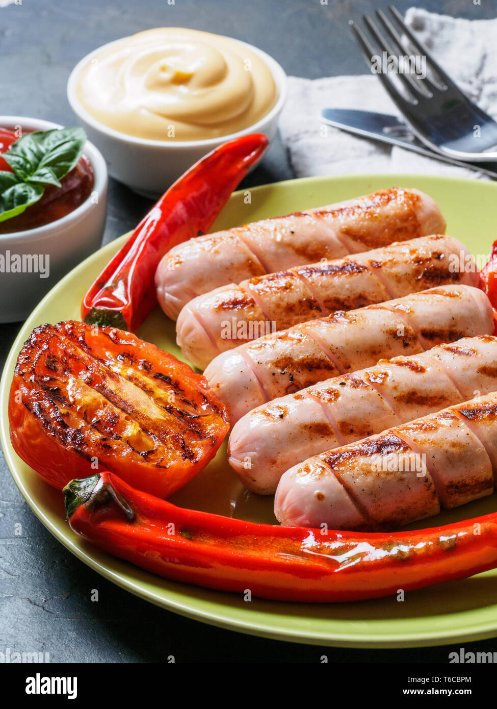 https://c8.alamy.com/comp/T6CBPM/close-up-view-of-chicken-homemade-sausages-with-sauces-ketchup-and-mustard-grilled-sausages-and-grilled-vegetables-in-green-plate-copy-space-vertical-T6CBPM.jpg