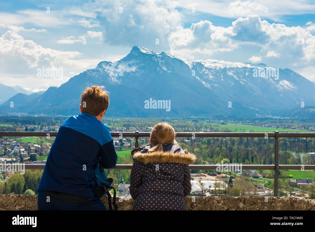 Children travel, rear view of children looking at an alpine mountain range from a viewing terrace in Salzburg Castle (Hohensalzburg), Austria. Stock Photo