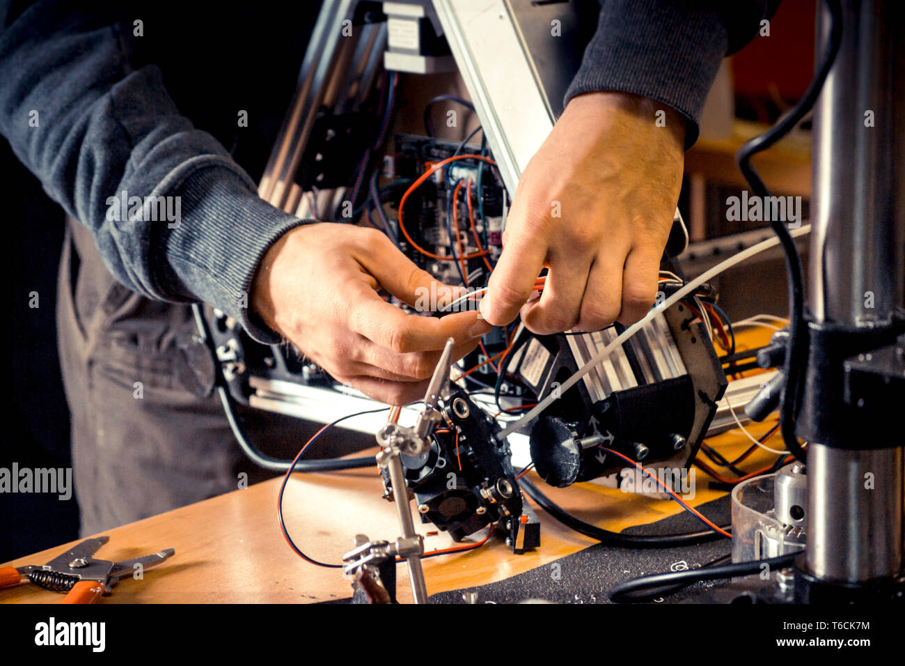 Two male masters work in the workshop with electronics, wires, 3d printer Stock Photo