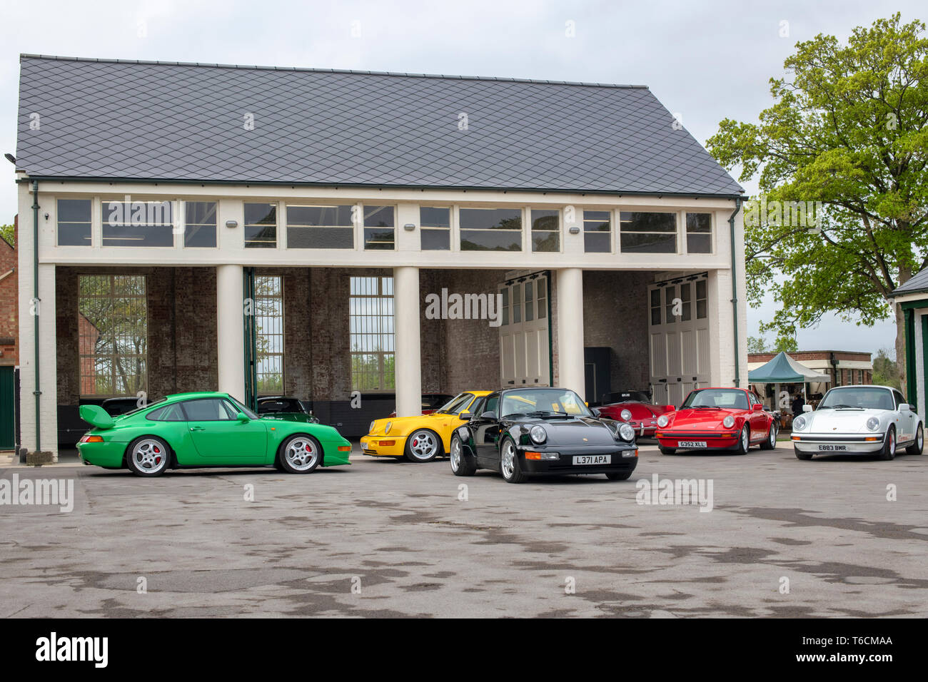 Porsche cars in front of a garage at Bicester heritage centre Drive It Day. Bicester, Oxfordshire, England Stock Photo