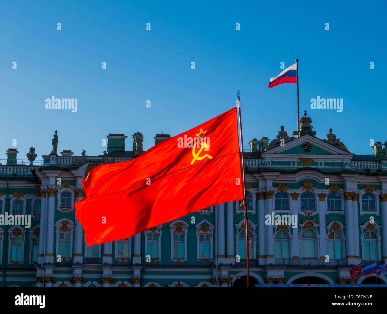 Soviet Union flag with the Russian flag and the Hermitage Museum in the background. In St. Petersburg, Russia Stock Photo