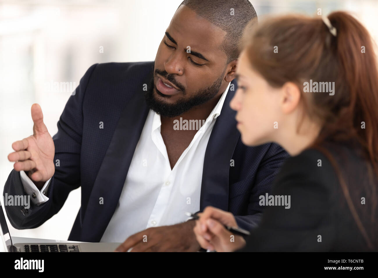 African american businessman mentor teaching caucasian intern with computer Stock Photo