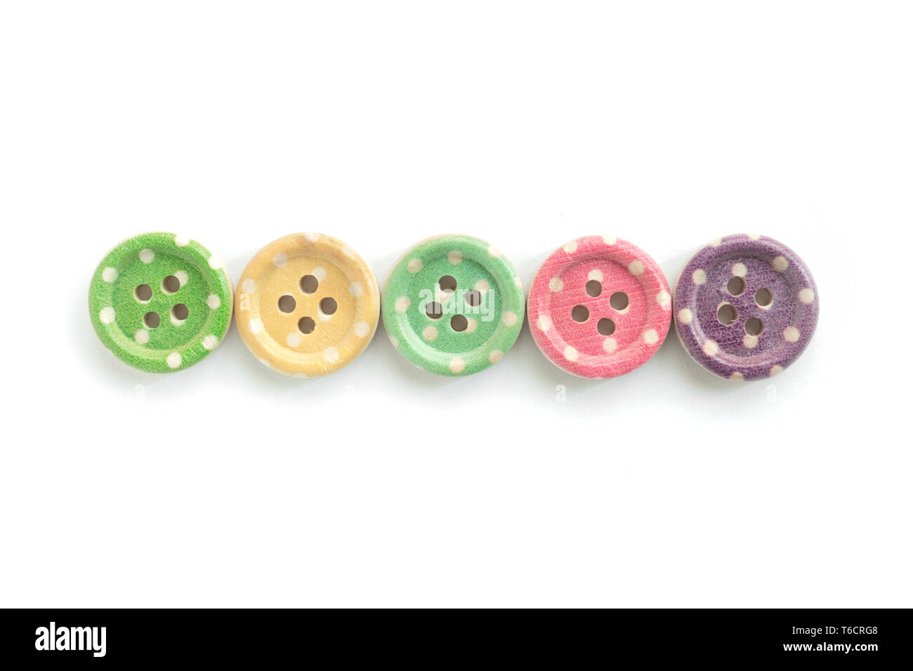 Wooden buttons with colorful stripes and colorful dots on a white background. Sewing Stock Photo