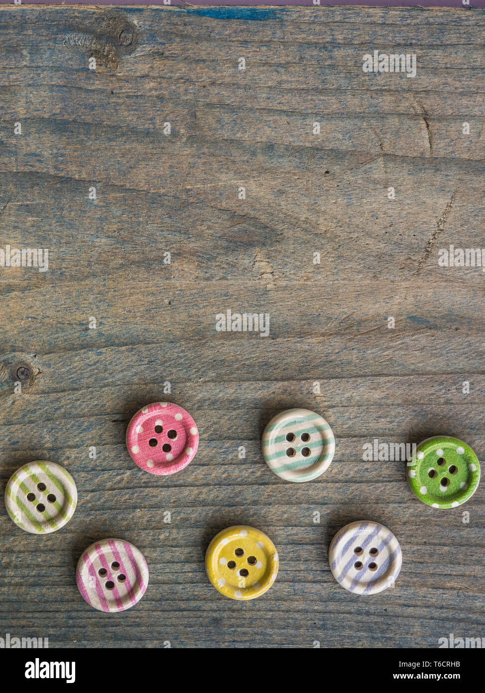 Wooden buttons with colorful stripes and colorful dots on a wooden background. Sewing Stock Photo