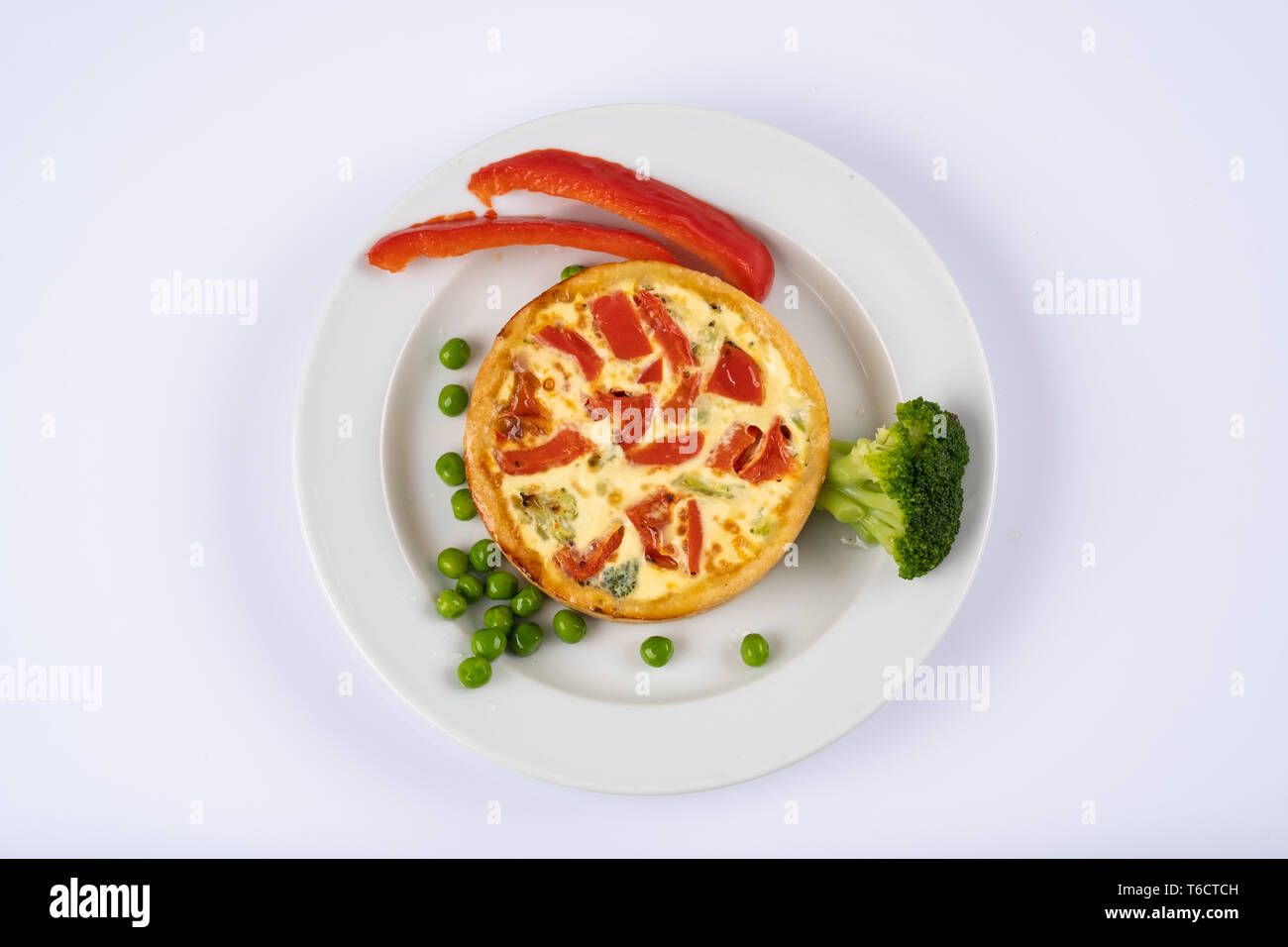 Broccoli cheddar mini savory pies on white plate. Delicious appetizers, snack, tapas. Flat lay. Tart or casserole with eggs, cheese, broccoli, bell, g Stock Photo