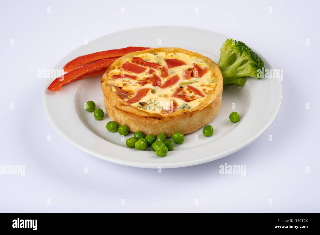 Broccoli cheddar mini savory pies on white plate. Delicious appetizers, snack, tapas. Flat lay. Tart or casserole with eggs, cheese, broccoli, bell, g Stock Photo