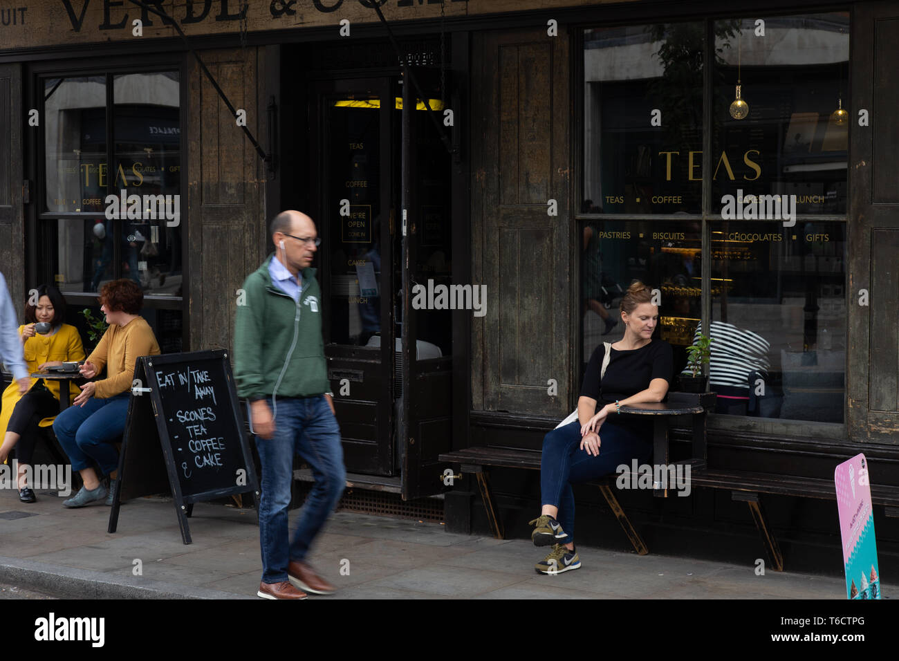 young woman seated in front of a cafe bar on the street in Spitalfields, London Stock Photo
