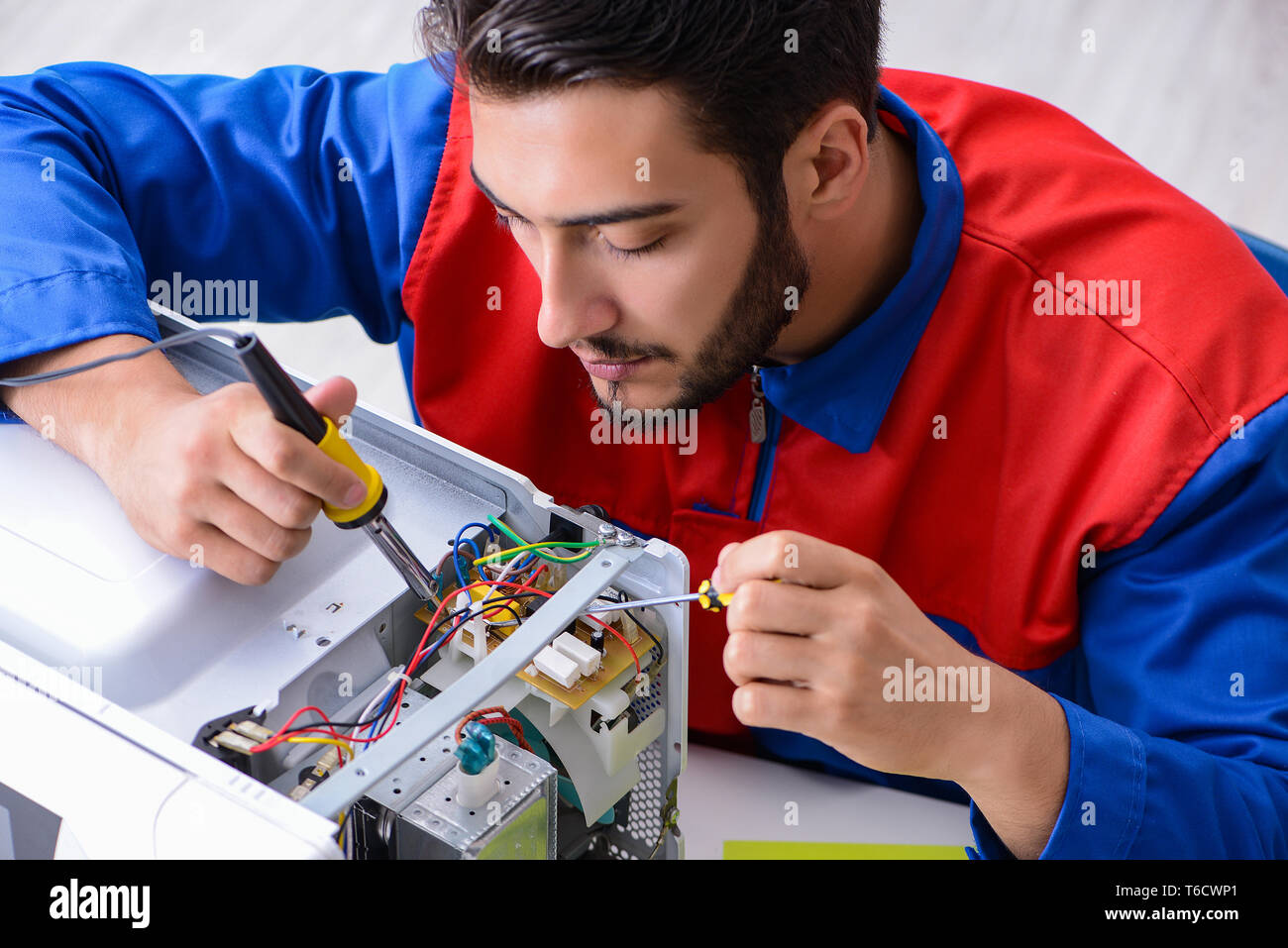 Young repairman fixing and repairing microwave oven Stock Photo