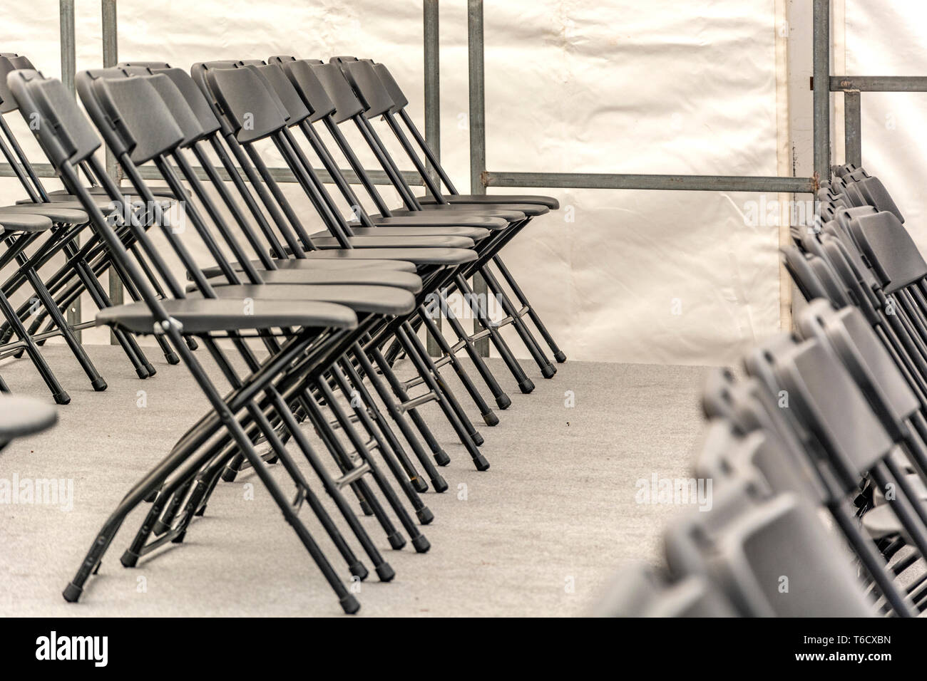 Rows of black folding chairs empty in a conference room Stock Photo
