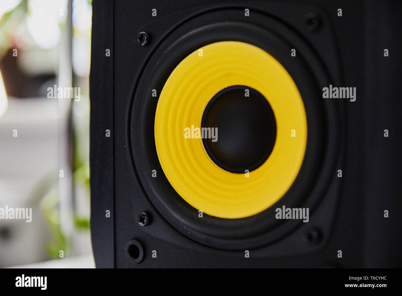 Black speaker studio monitor with yellow membrane on the desk in the modern apartment Stock Photo