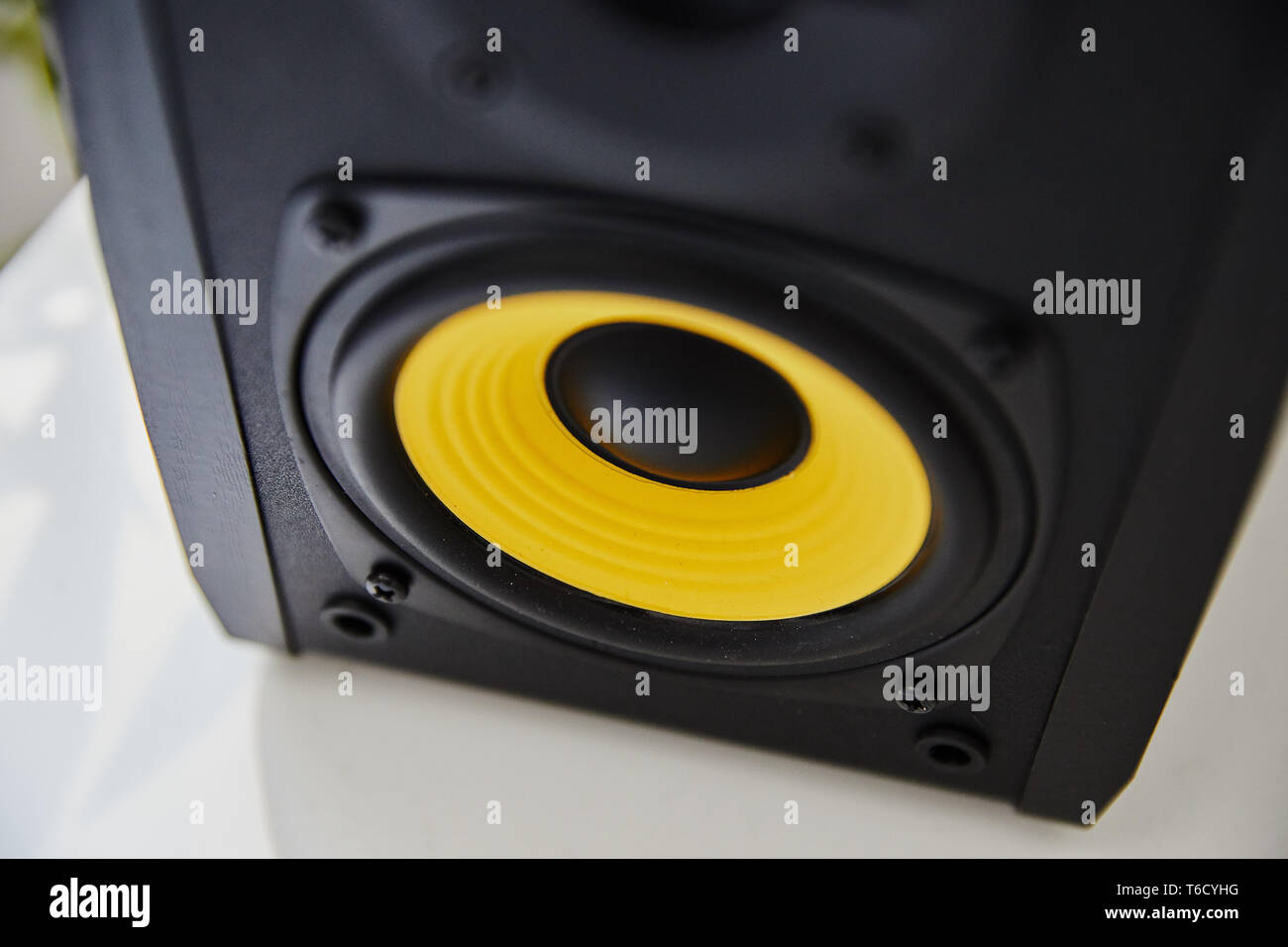 Black speaker studio monitor with yellow membrane on the desk in the modern apartment Stock Photo