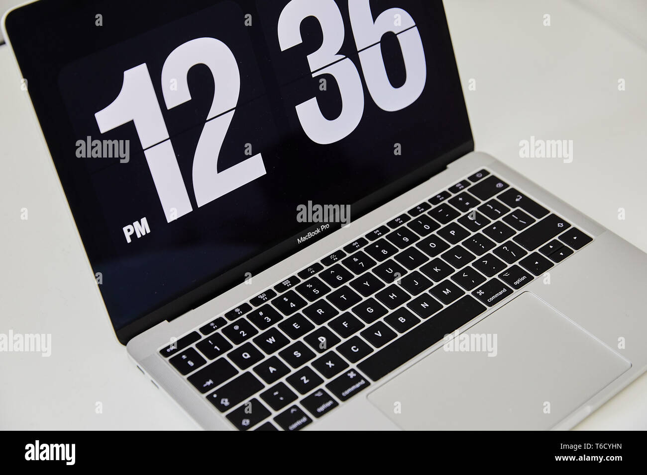 Apple MacBook Pro notebook with the clock screensaver on the big white Ikea  desk office with the black yellow speakers, iPhone in the background Stock  Photo - Alamy