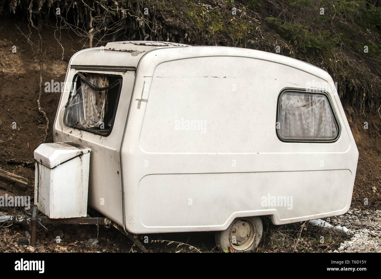 Old abandoned weathered small white vintage caravan Stock Photo