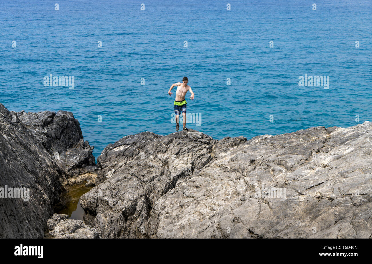 young man on a cliff getting out of balance Stock Photo