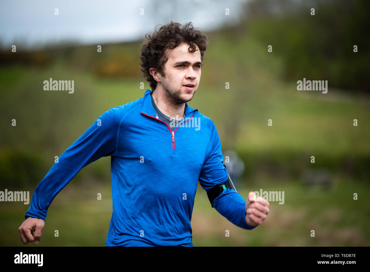 Young man in mid 20s exercising and keeping fit by running in a park Stock Photo