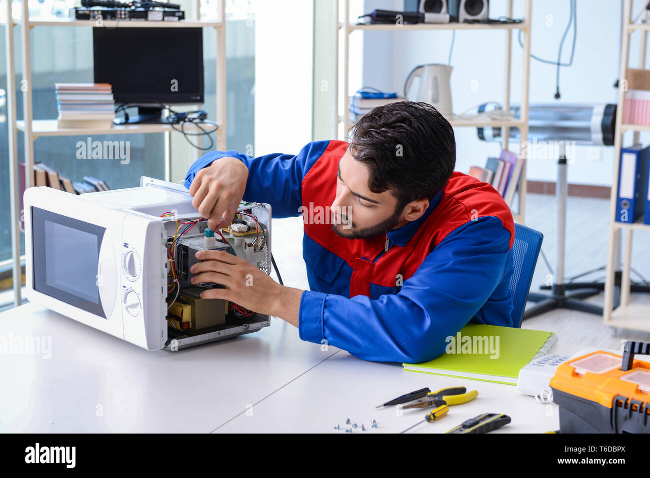 Young repairman fixing and repairing microwave oven Stock Photo