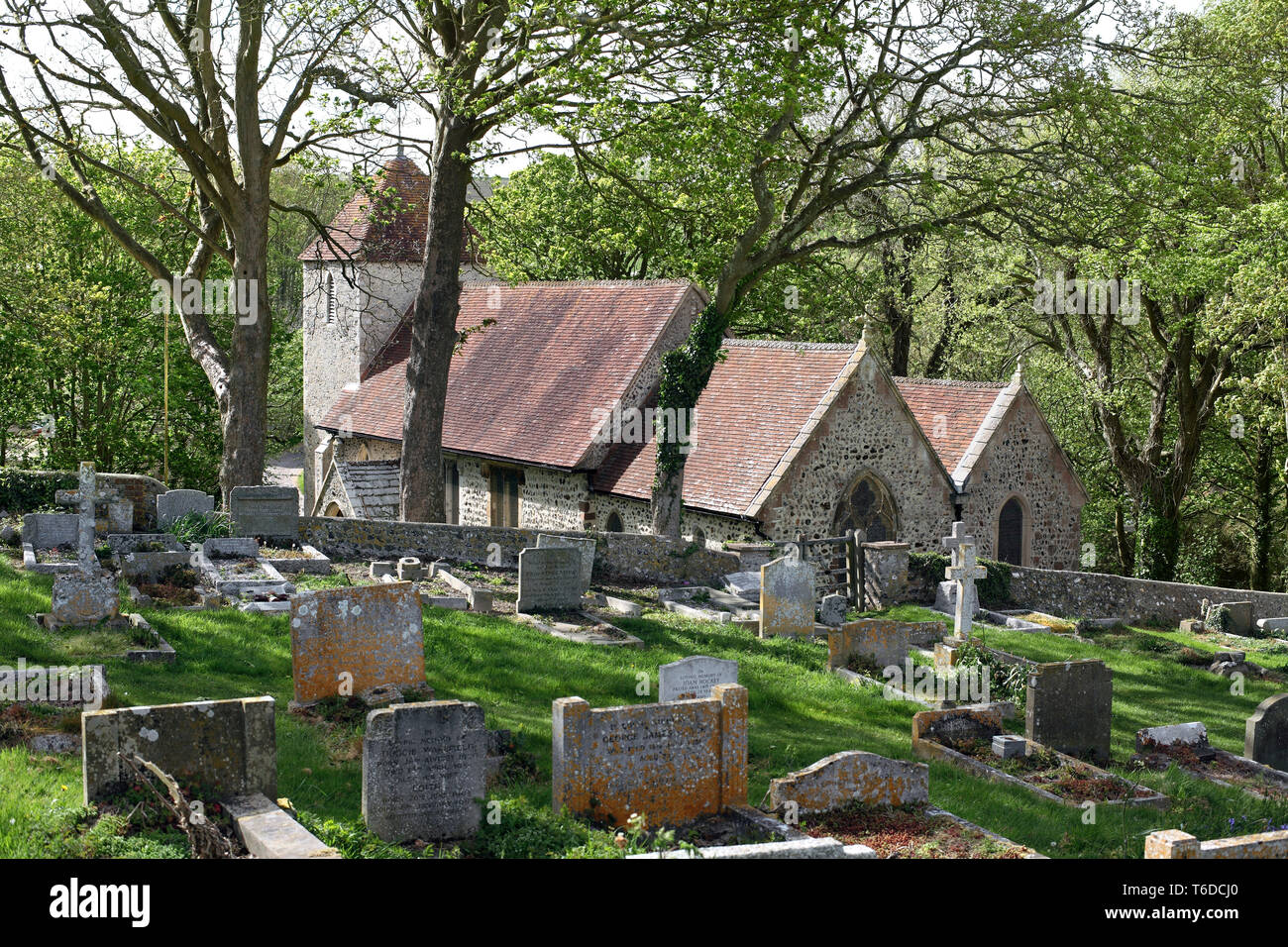 The Church of St Lawrence, Telscombe, bathed in spring sunshine, nestles among trees in a South Downs valley, East Sussex. Stock Photo