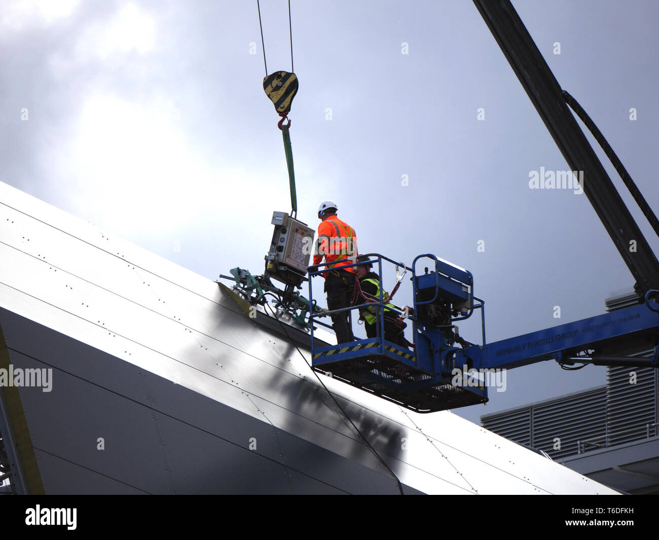 Two construction workers on a platform taking a panel from a crane Stock Photo