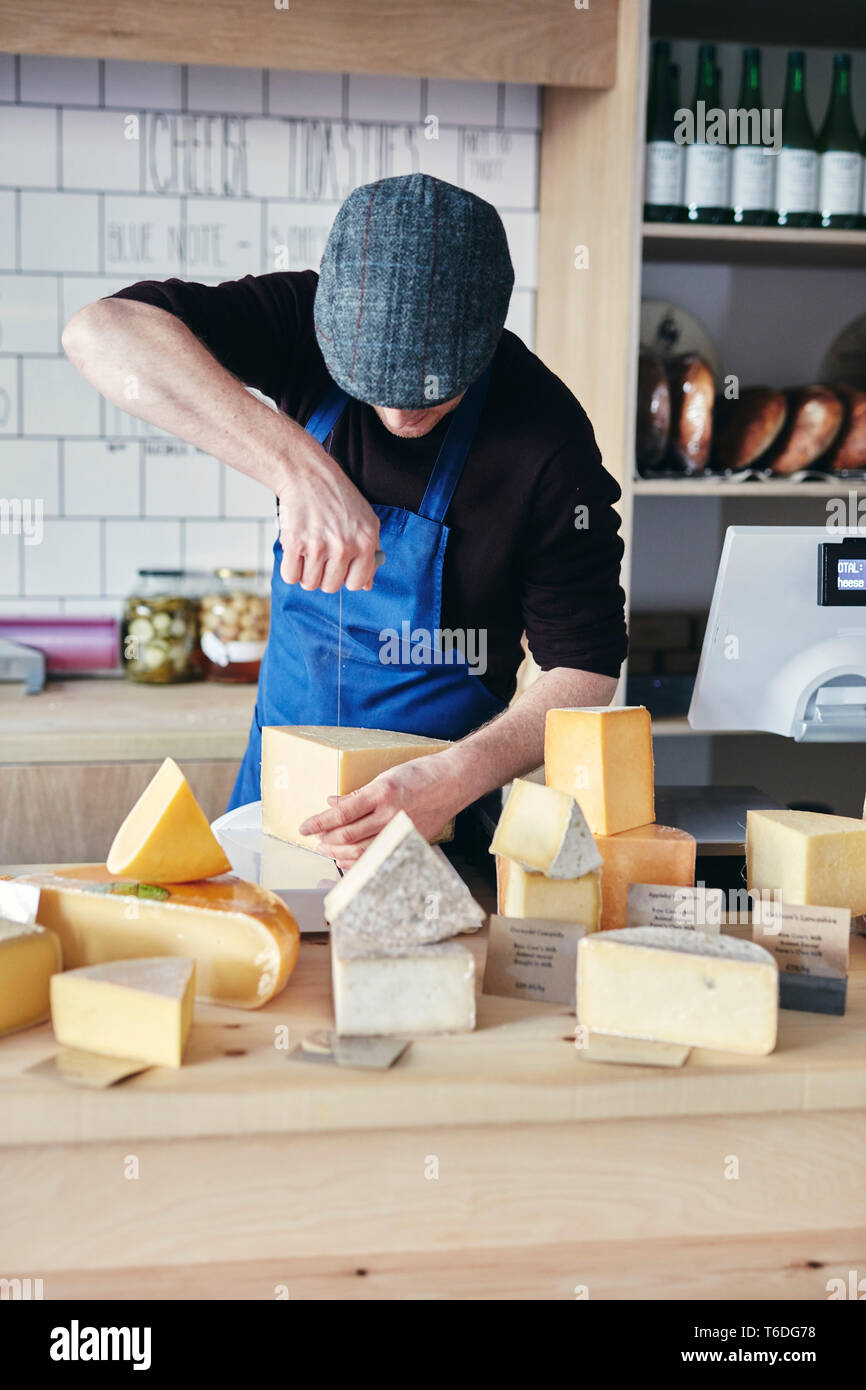 Cheesemonger cutting cheese using cheese wire Stock Photo