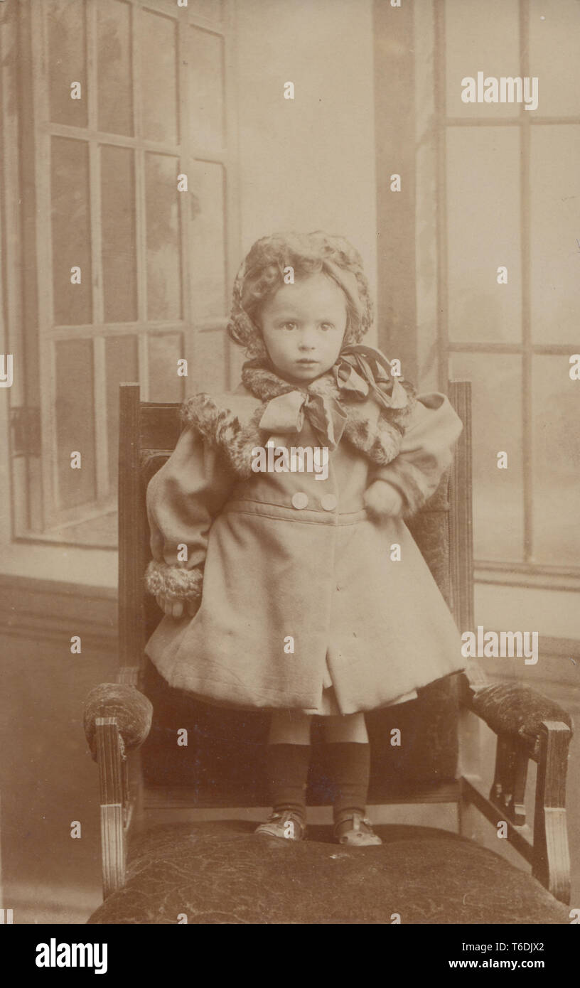 Vintage Photographic Portrait Postcard Showing a Young Girl Stood on a Chair Stock Photo