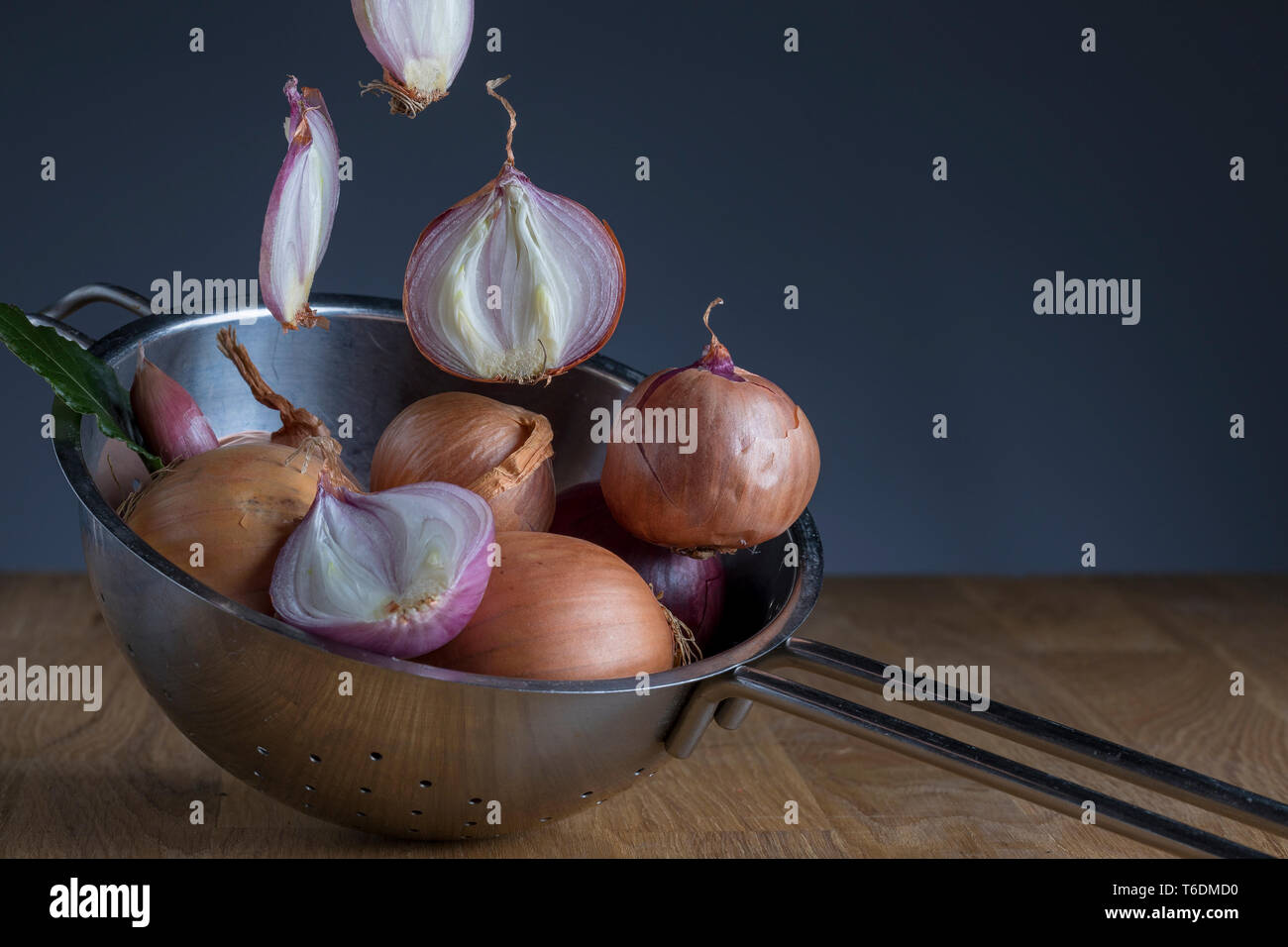 Onions tumbling into a sieve Stock Photo