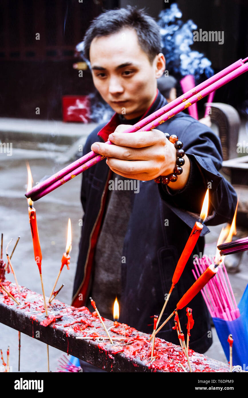 Chengdu, Sichuan province, China : A young man burns incense joss sticks at the Qingyang Gong Taoist temple, the oldest and most extensive Taoist temp Stock Photo