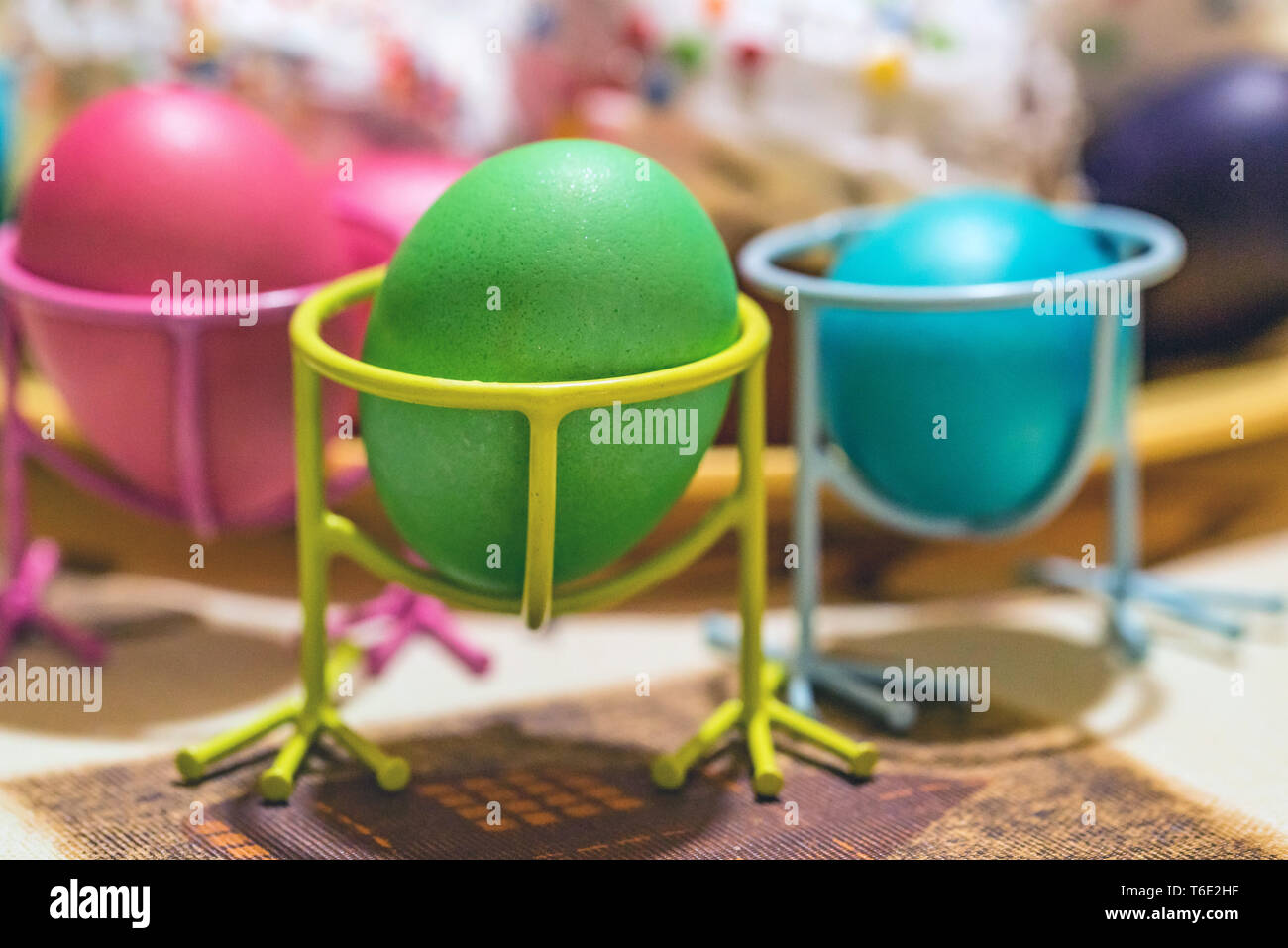 Three Easter painted eggs in holders on table Stock Photo