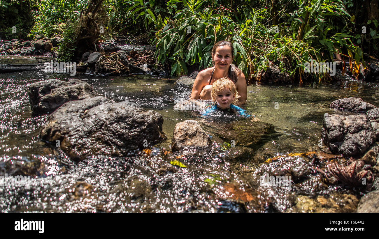 A nice photo of smiling mother and son enjoying the beautiful natural ecotermales in a tropical rain forest at Tabacon, La Fortuna, Costa Rica. Stock Photo