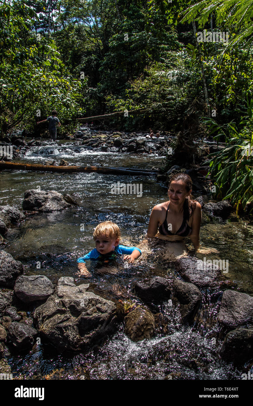A nice photo of smiling mother and son enjoying the beautiful natural ecotermales in a tropical rain forest at Tabacon, La Fortuna, Costa Rica. Stock Photo