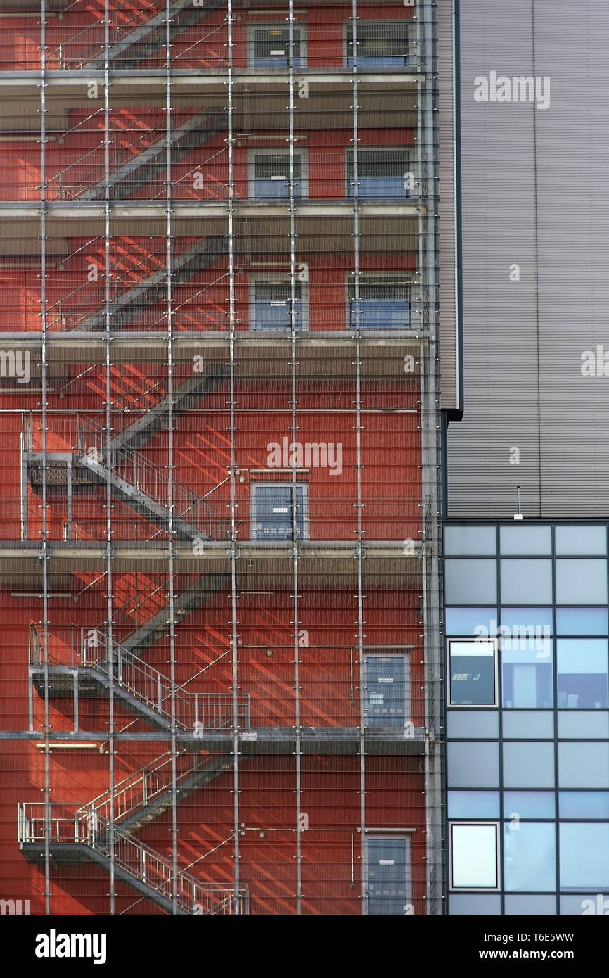 The exterior staircase of a residential and commercial building casts shadows behind bars. Stock Photo