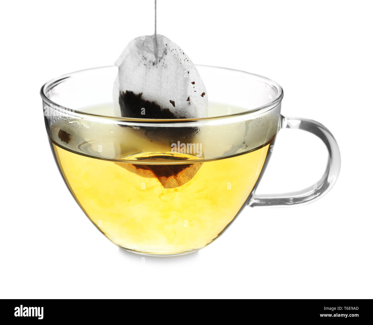 Brewing hot tea in glass cup using teabag, on white background Stock