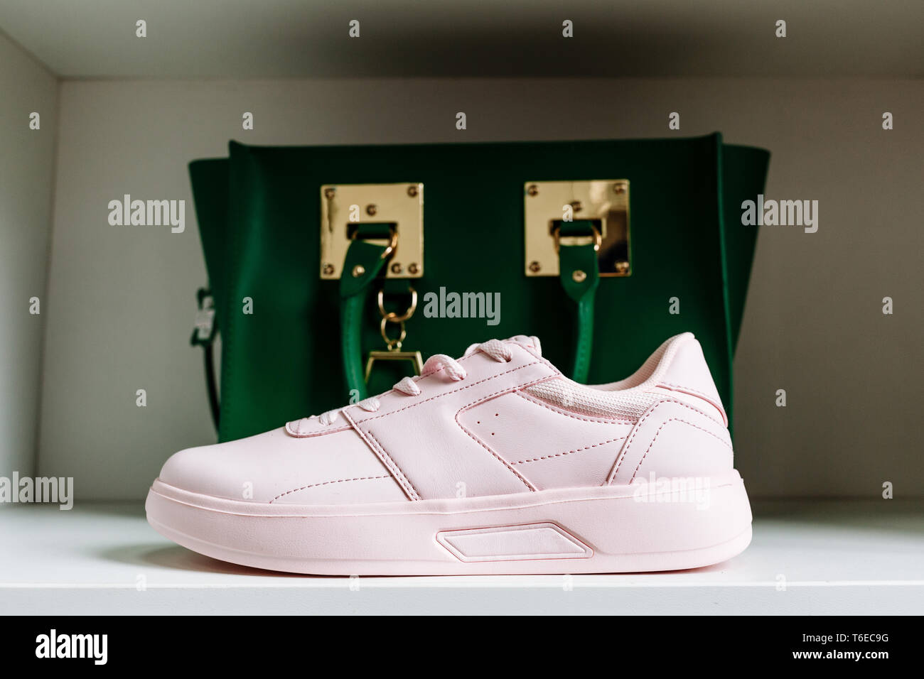 fashionable pink sneakers with thick soles and a green bag in the background on the white shelf of the store Stock Photo